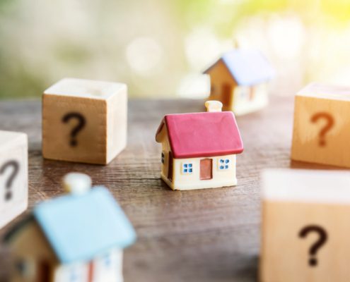 Small model house surrounded by question mark blocks on wooden table