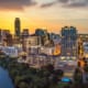 Austin, Texas skyline at sunset with river and illuminated buildings.