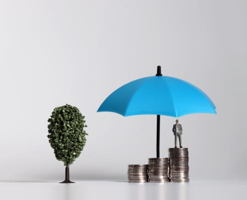 a model umbrella with a figure standing on coins under it and a toy tree next to it