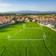 Aerial view of green field bordered by suburban homes, with a dashed outline and location pins