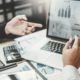 Business professionals reviewing financial charts and graphs on laptop during meeting