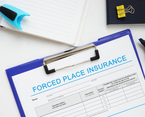 Forced place insurance form on clipboard with office supplies on desk