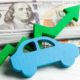 Blue wooden car shape and green upward arrow in front of stacked US $100 bills