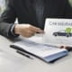 an insurance agent pointing to a tablet with car insurance graphic on it