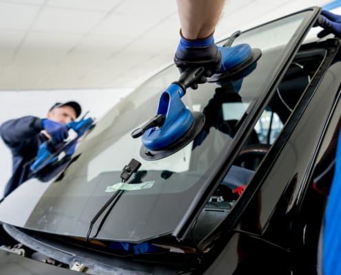 a car wind shield getting replaced by two mechanics