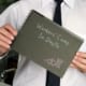 Business professional holding a notebook labeled “Workers’ Comp In-Depth” while wearing a white shirt and black tie